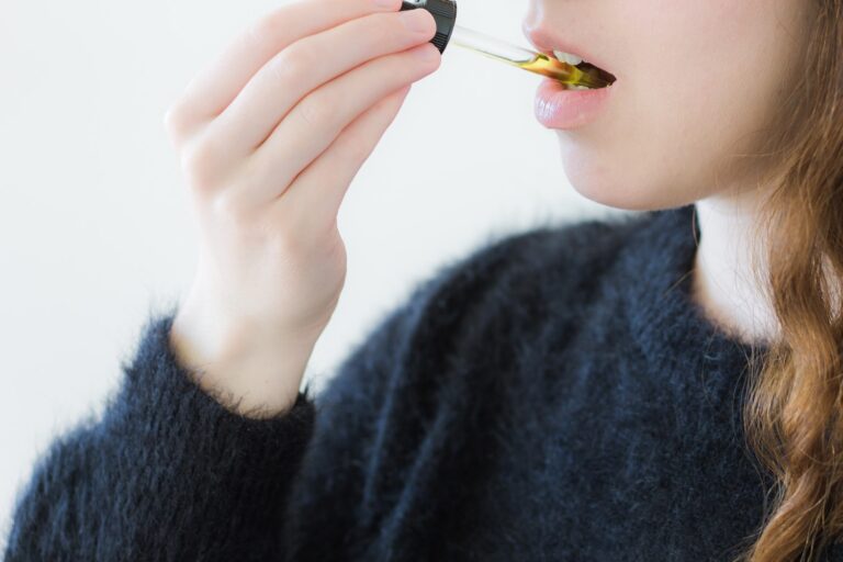 woman consuming cannabis using sublingual tincture